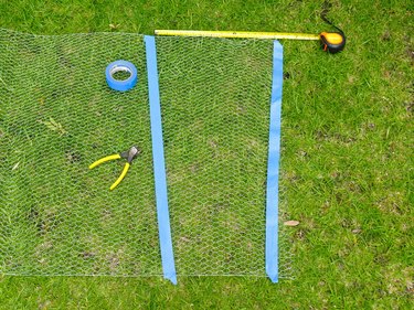 Flat piece of chicken wire with blue tape marking the taper of the torso.