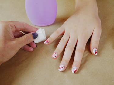 A cotton pad and polish remover cleaning around the nails.