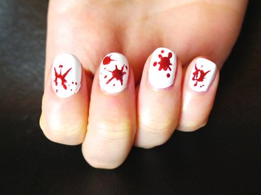 Large, single splats of blood on white nails.