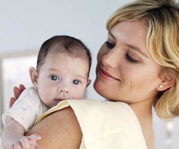 mom burping newborn baby on her shoulder