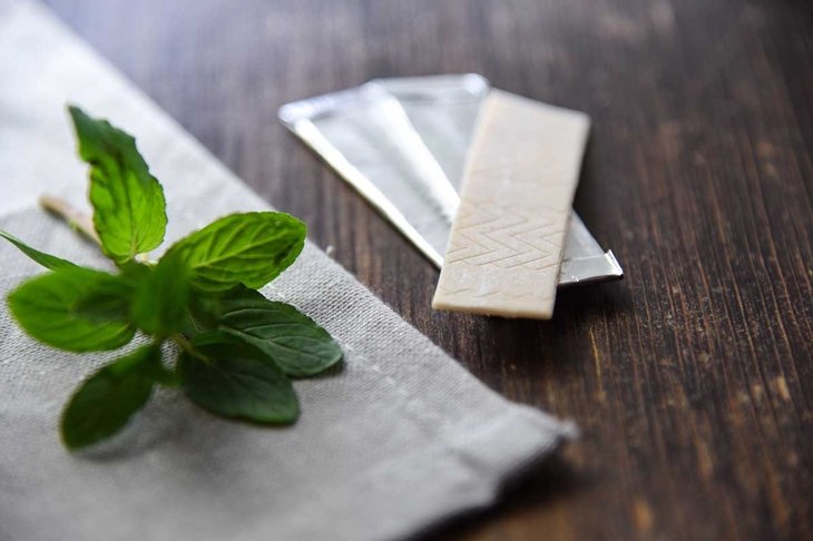 Chewing gums with mint leafs on wooden table