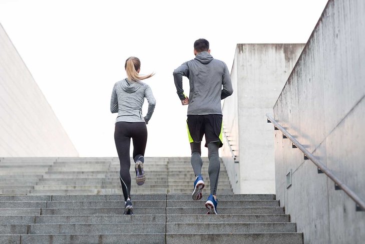 fitness, sport, people, exercising and lifestyle concept - couple running upstairs on city stairs