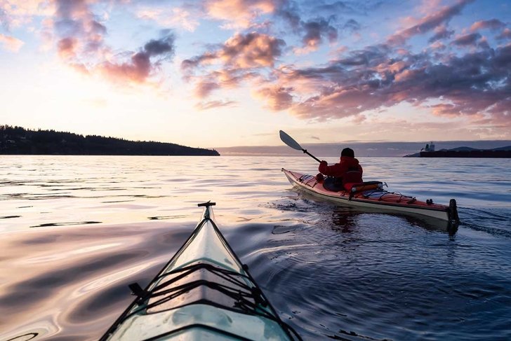 Adventurous Man Sea Kayaking in the Pacific Ocean. Dramatic Colorful Sky Art Render. Taken in Jericho, Vancouver, British Columbia, Canada.