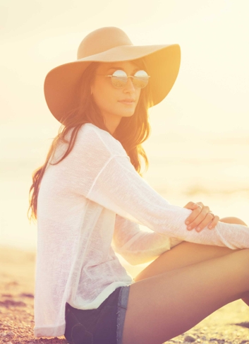 Woman sits in the sun and shows how you can be sun safe using natural sun lotion